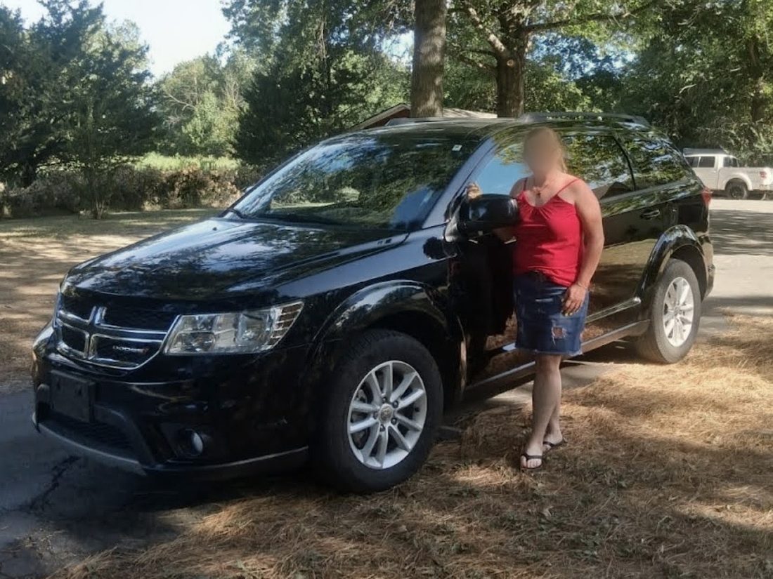 A recipient standing beside the crossover SUV she received through the Automobile Program